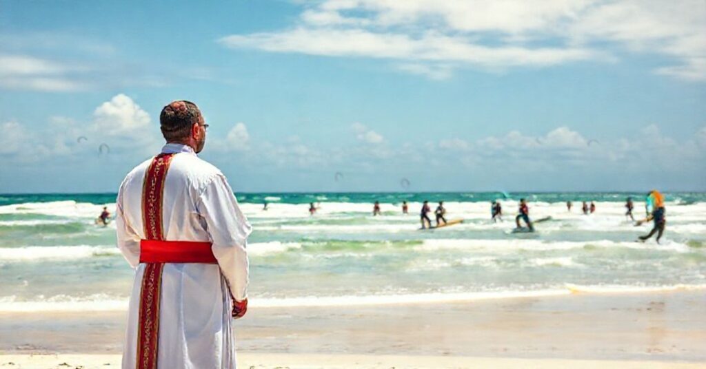 A Catholic priest in traditional vestments stands solemnly on a Zanzibar beach during a secular kitesurfing competition, symbolizing the spiritual void of naturalistic peace without Christ's Kingship.