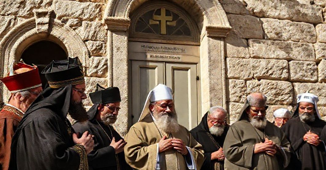 Jerusalem church leaders in solemn prayer before a Lutheran hospital, reflecting secular humanitarianism over supernatural charity.