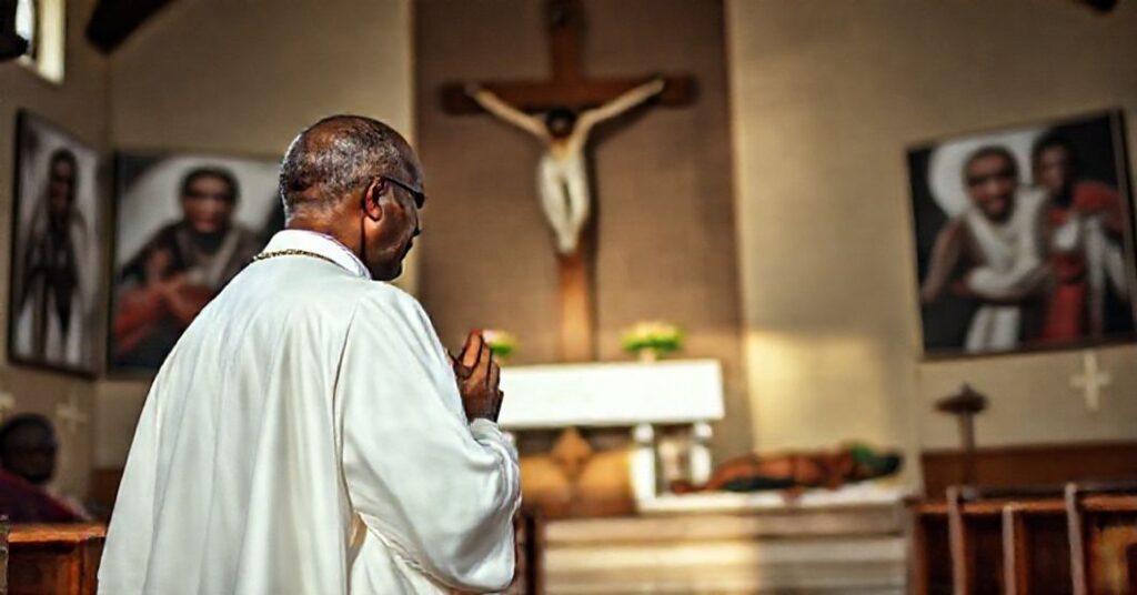 A Catholic priest praying in a Nigerian church amidst images of martyrs, highlighting the persecution of Christians and the need for Christ's social reign.