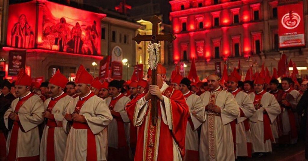 A Catholic bishop leads a traditional procession under red-lit buildings during 'Red Week 2025,' symbolizing the clash between true martyrdom and modernist activism.